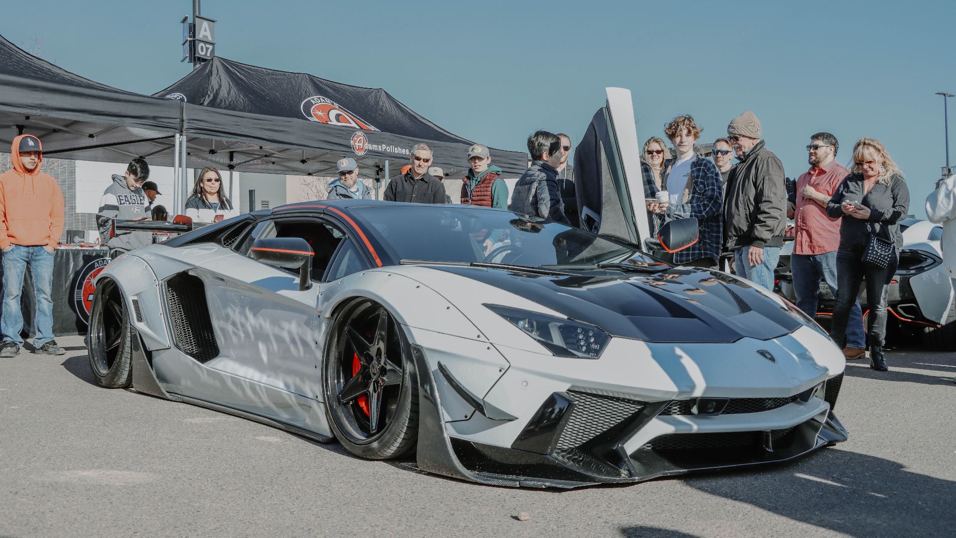 A stunning Lamborghini Aventador with wing doors open on display at a car show in Denver.