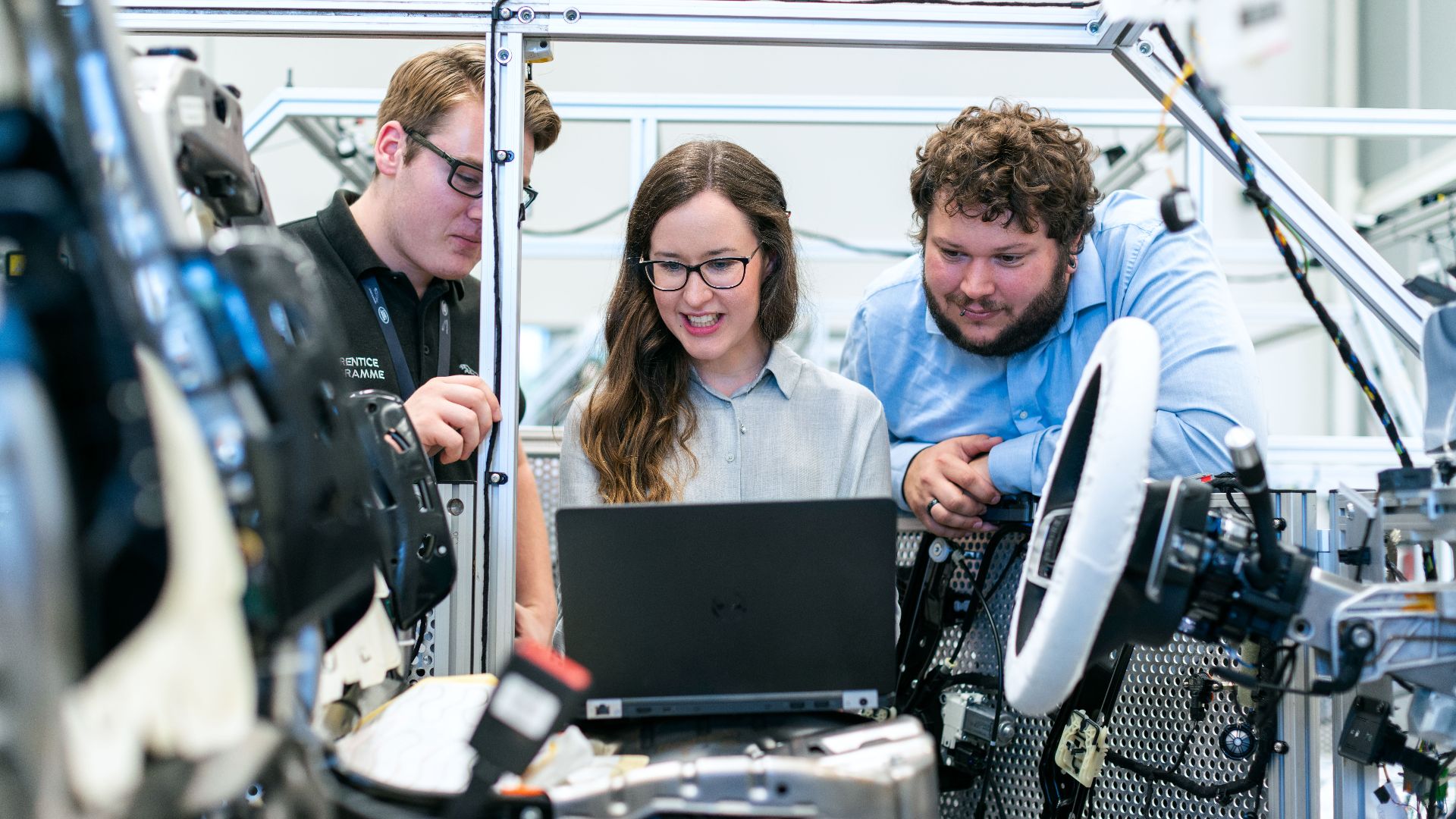 Engineers collaborating on a car project in a modern automotive workshop using advanced technology.