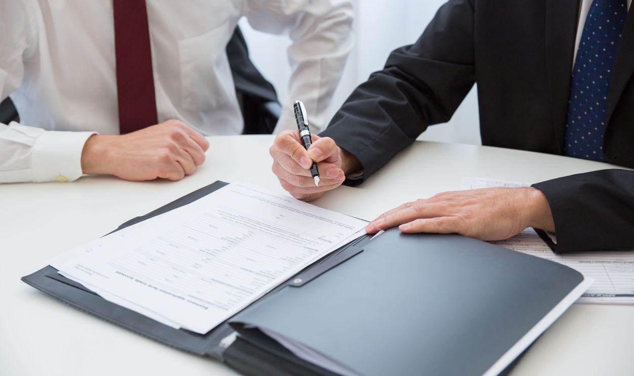 Two professionals signing a contract at a business meeting in an office