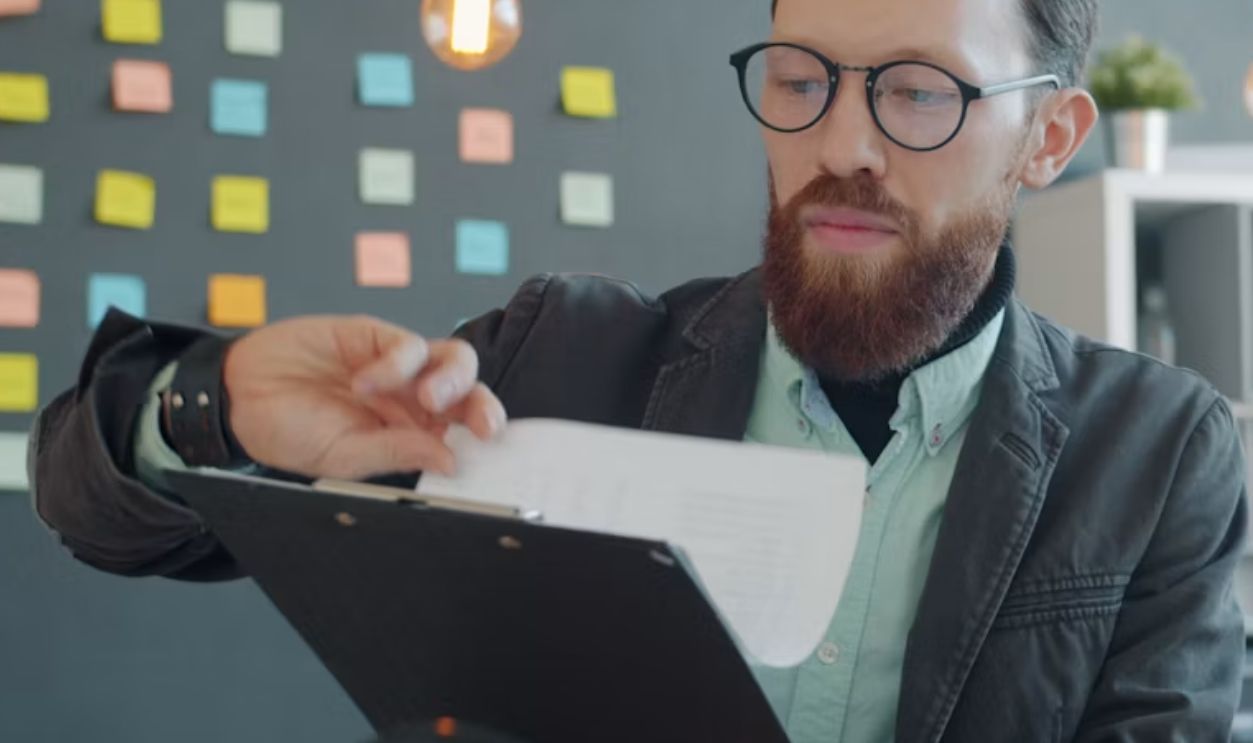 Man in glasses reviewing documents at desk