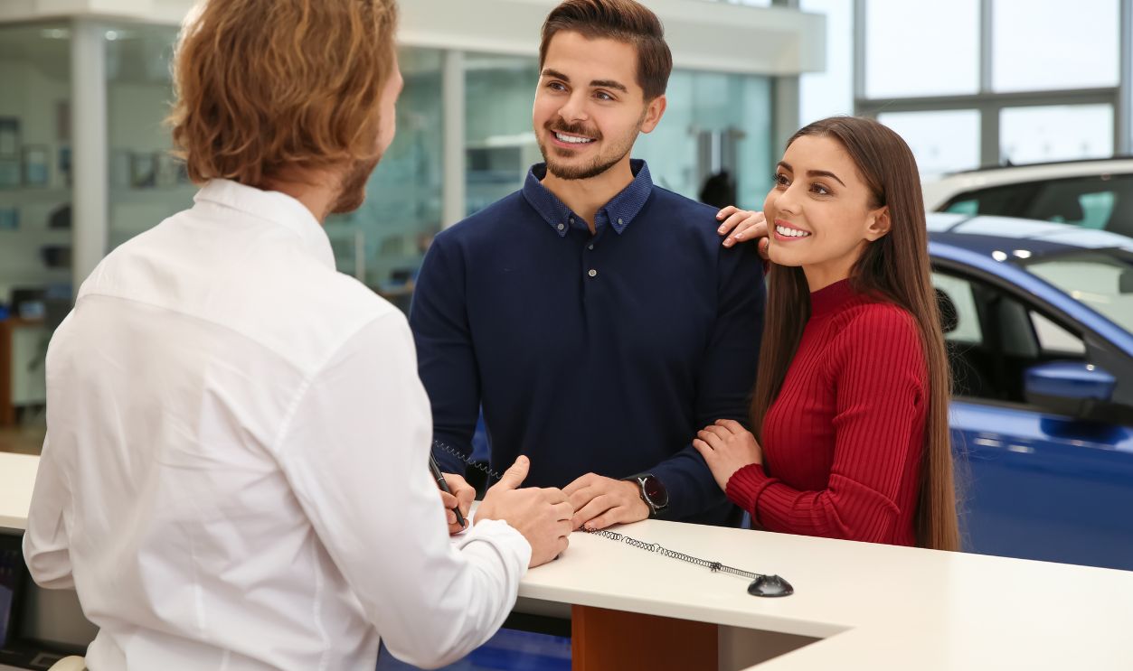 Car salesman and young couple in dealership