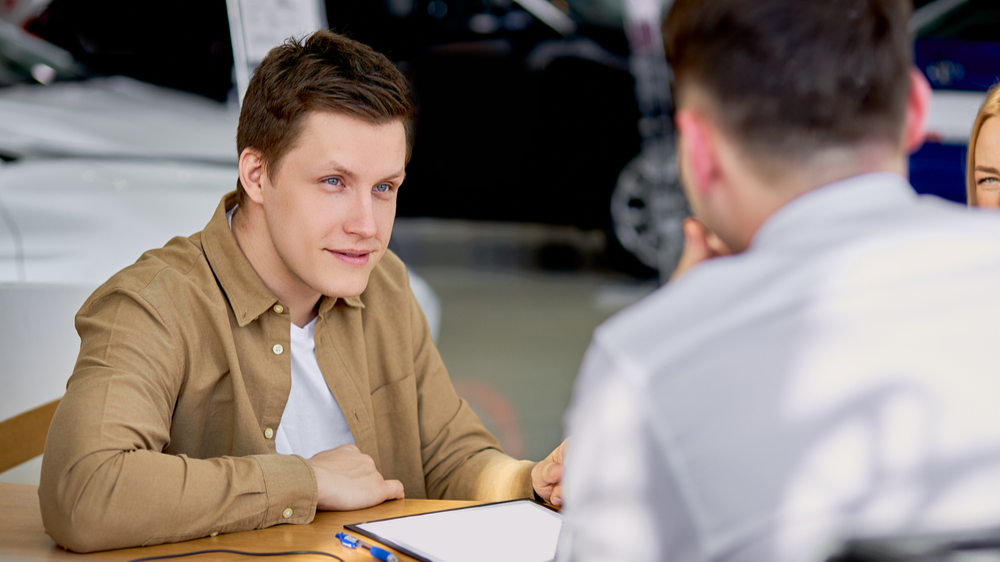 serious customer listen to salesman before signing document, making purchase in dealership
