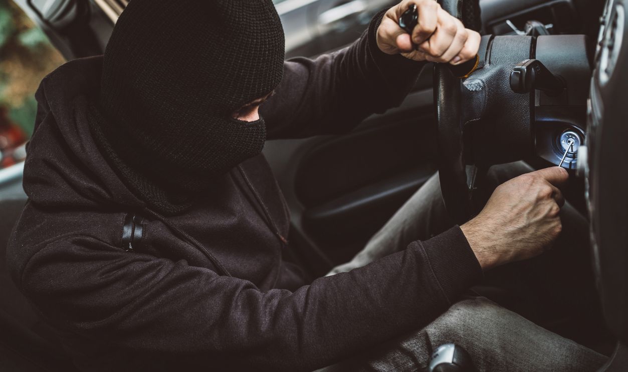 Car thief trying to start car with screwdriver in ignition. Car thief, car theft