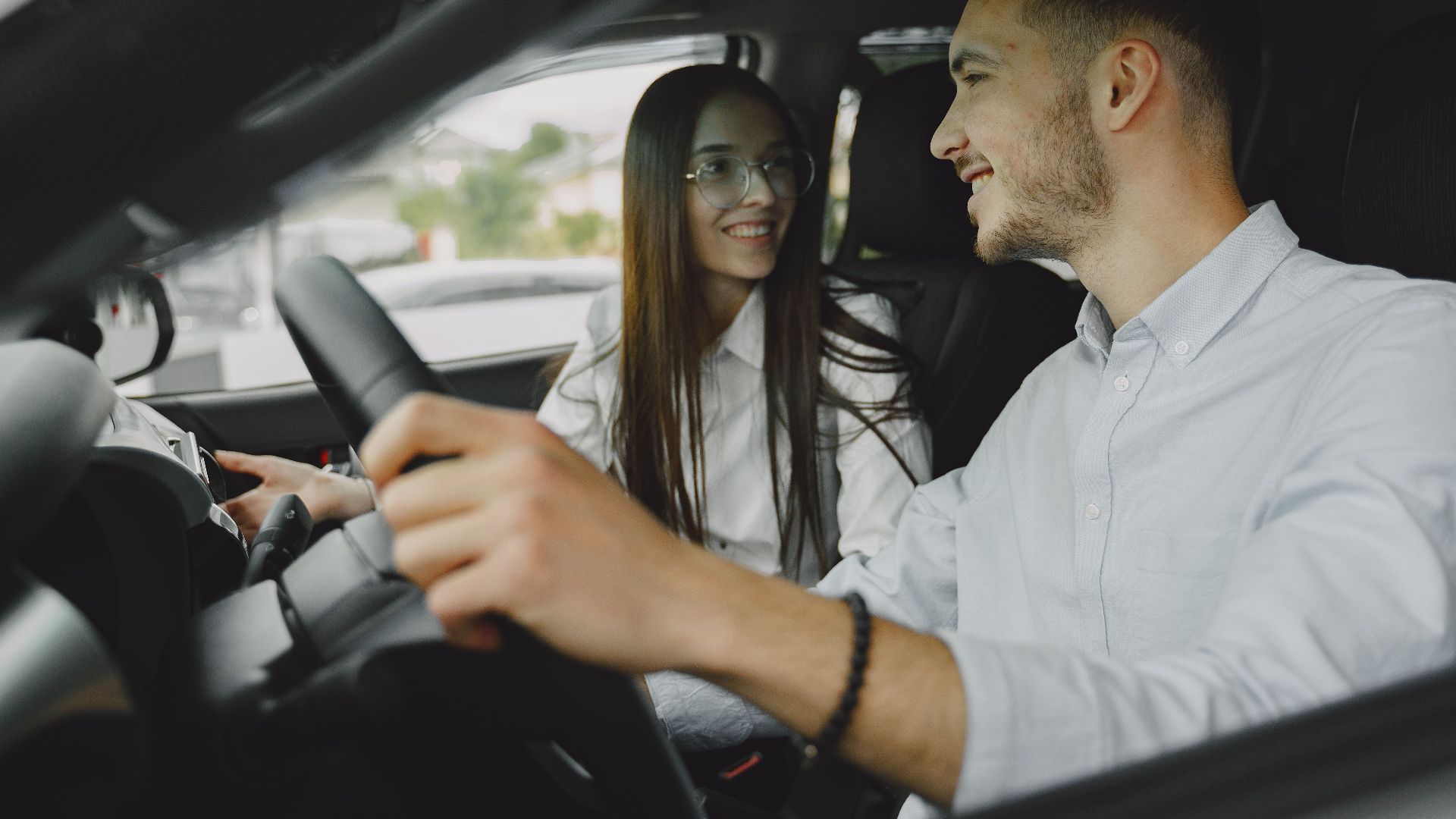 A smiling couple driving together in a car, enjoying their time on the road.