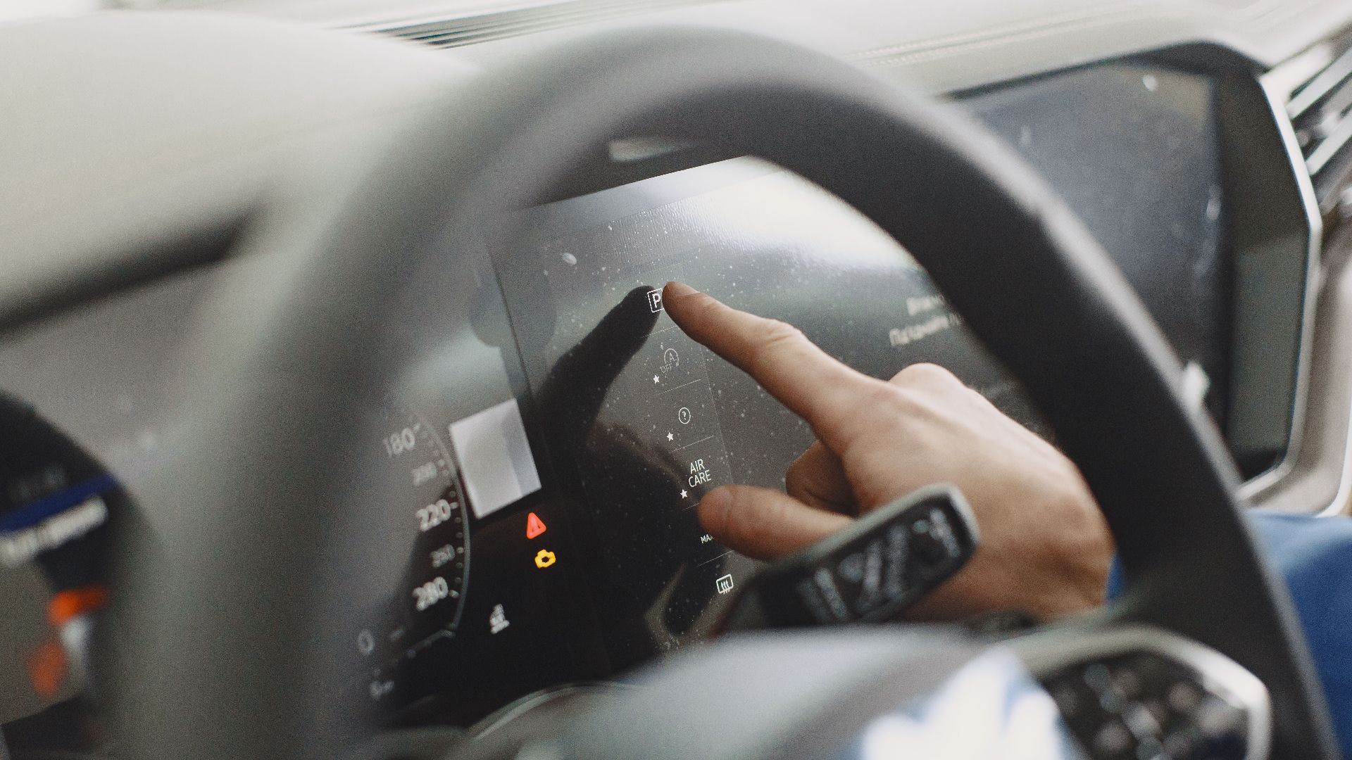 Close-up of a hand interacting with a car's digital dashboard. Modern technology and driving interface.