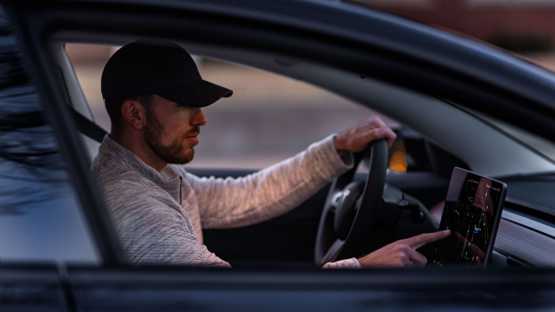 A man interacts with a touchscreen inside an electric car, driving through Dallas, TX.