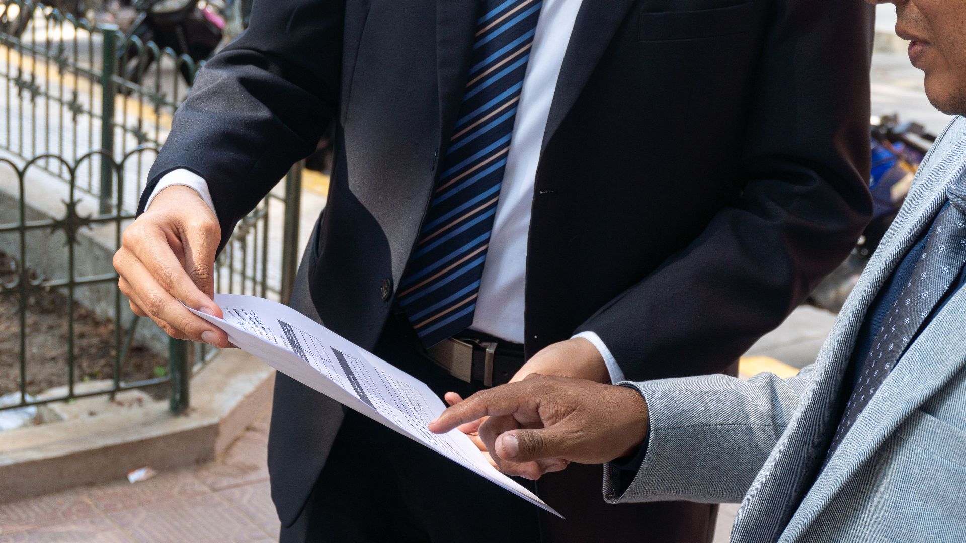 Two business professionals discussing and exchanging documents outdoors in Piura, Peru.