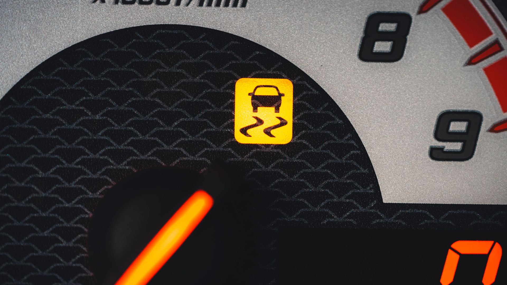 Close-up of a car dashboard showing a yellow traction control warning light.