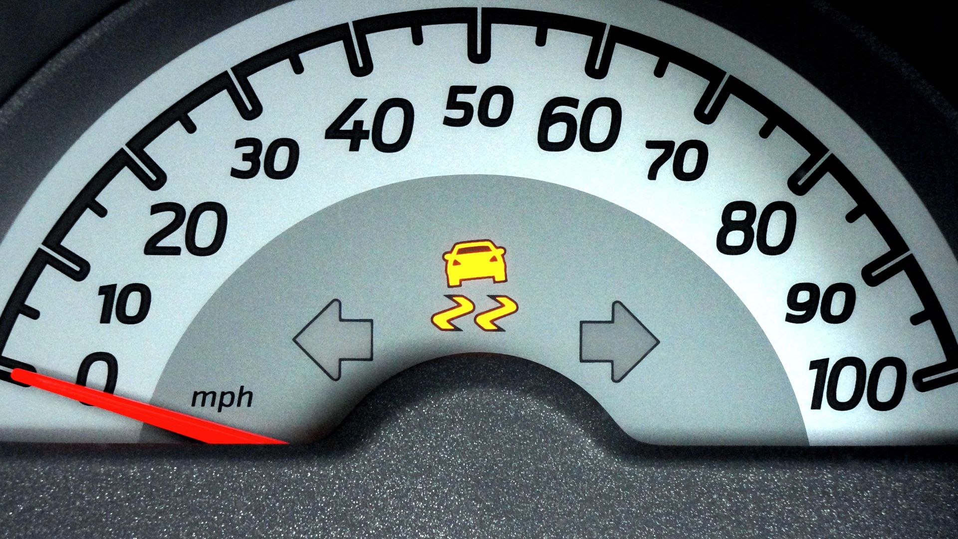 Close-up of a car speedometer displaying a warning indicator. Ideal for automotive themes.