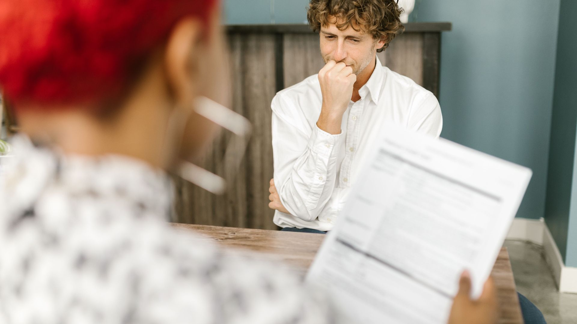 Man reflecting during a job interview in an office setting, highlighting thoughtfulness.