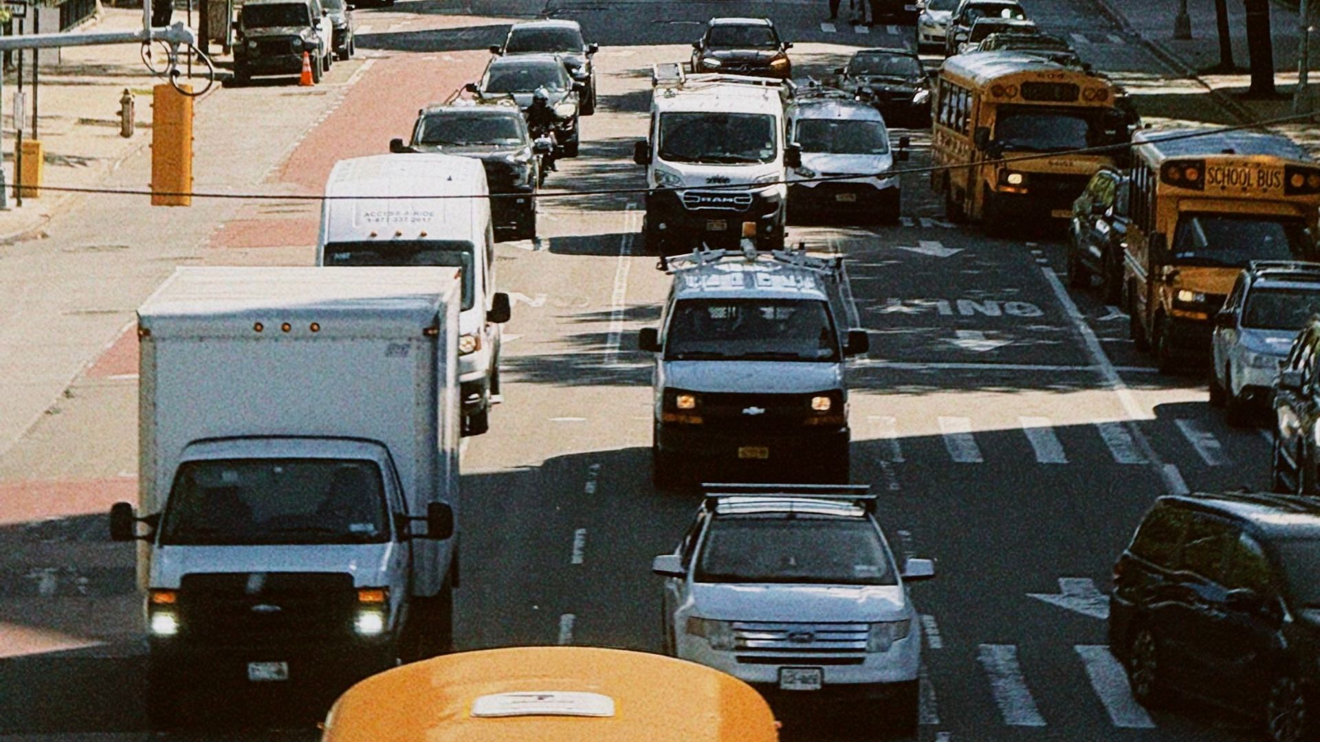 Bustling street scene with cars and buses under a clear sky in New York City.