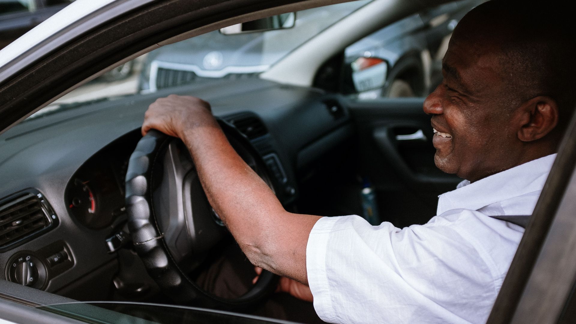 Smiling African American man in a car, enjoying a drive. Captured in a relaxed and candid moment.
