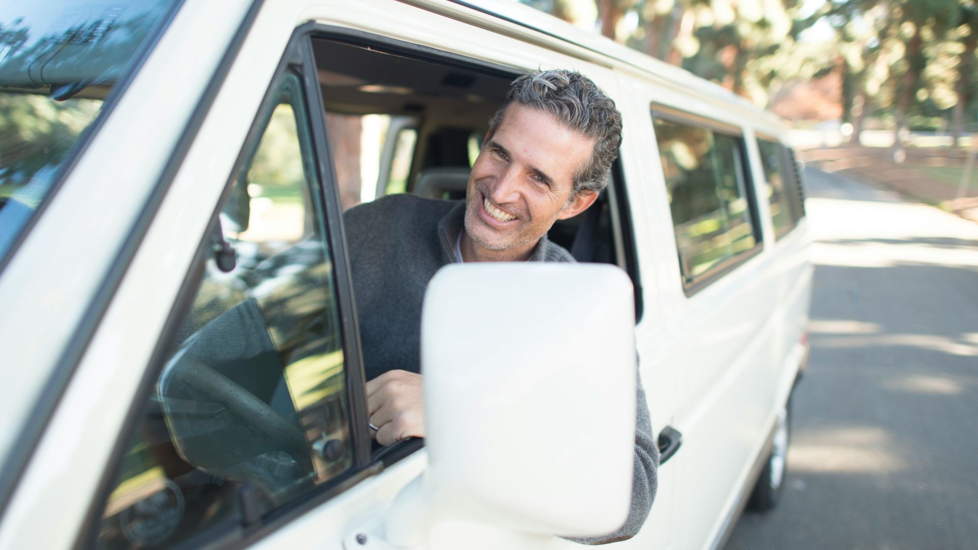 man in gray sweater leaning on van window