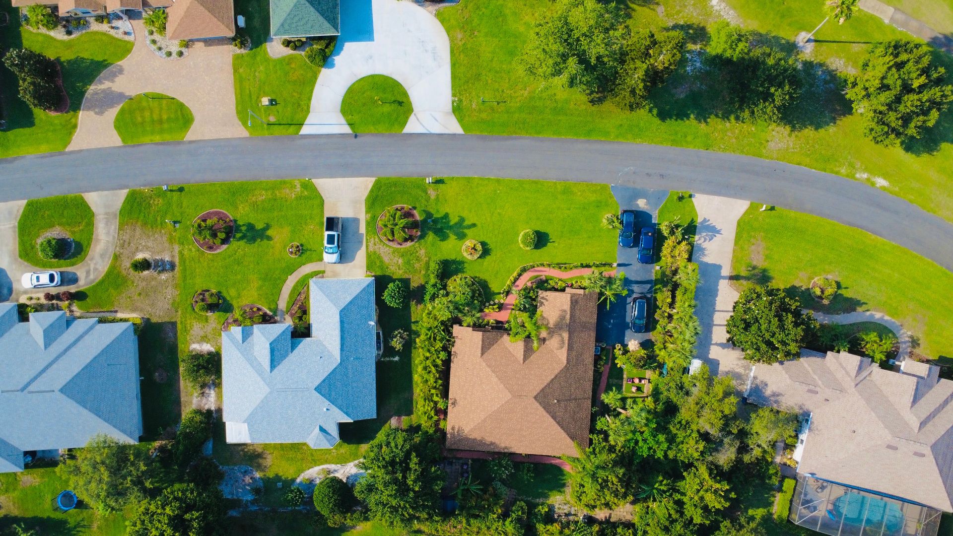 Aerial shot of a suburban neighborhood showcasing houses, driveways, and green lawns.