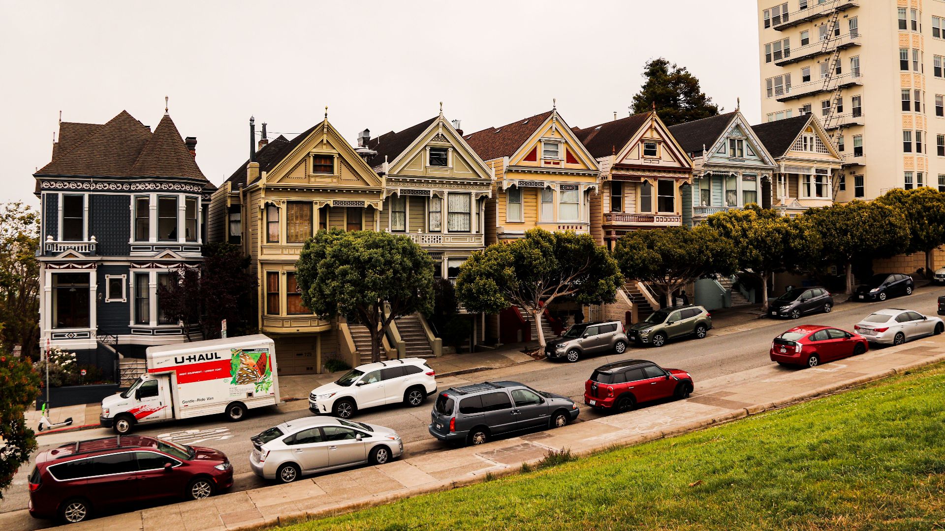 Historic Painted Ladies homes with parked cars in San Francisco, showcasing Victorian architecture.