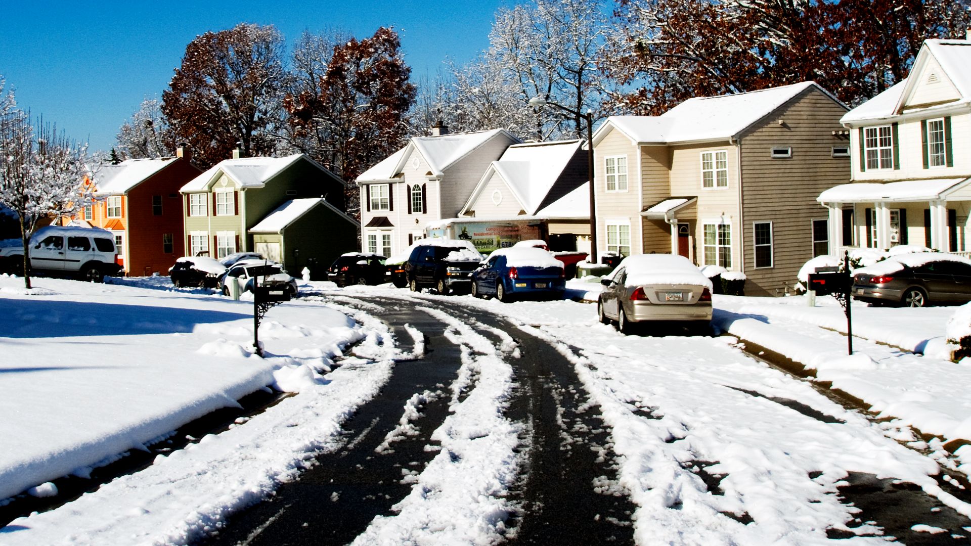 A picturesque snowy street view in Austell, Georgia with colorful houses and a clear blue sky.