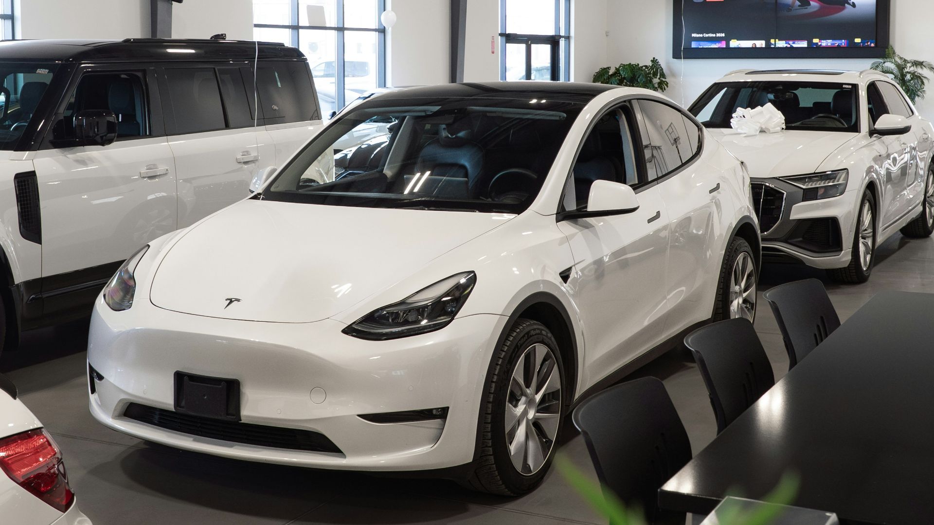 White tesla model y parked inside a showroom.