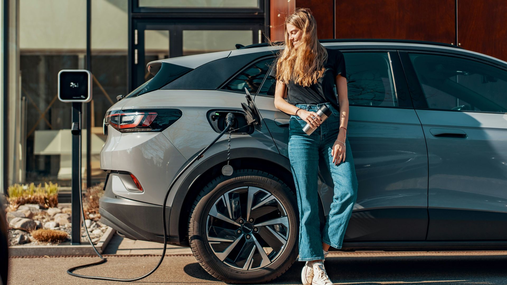 a woman standing next to a blue car