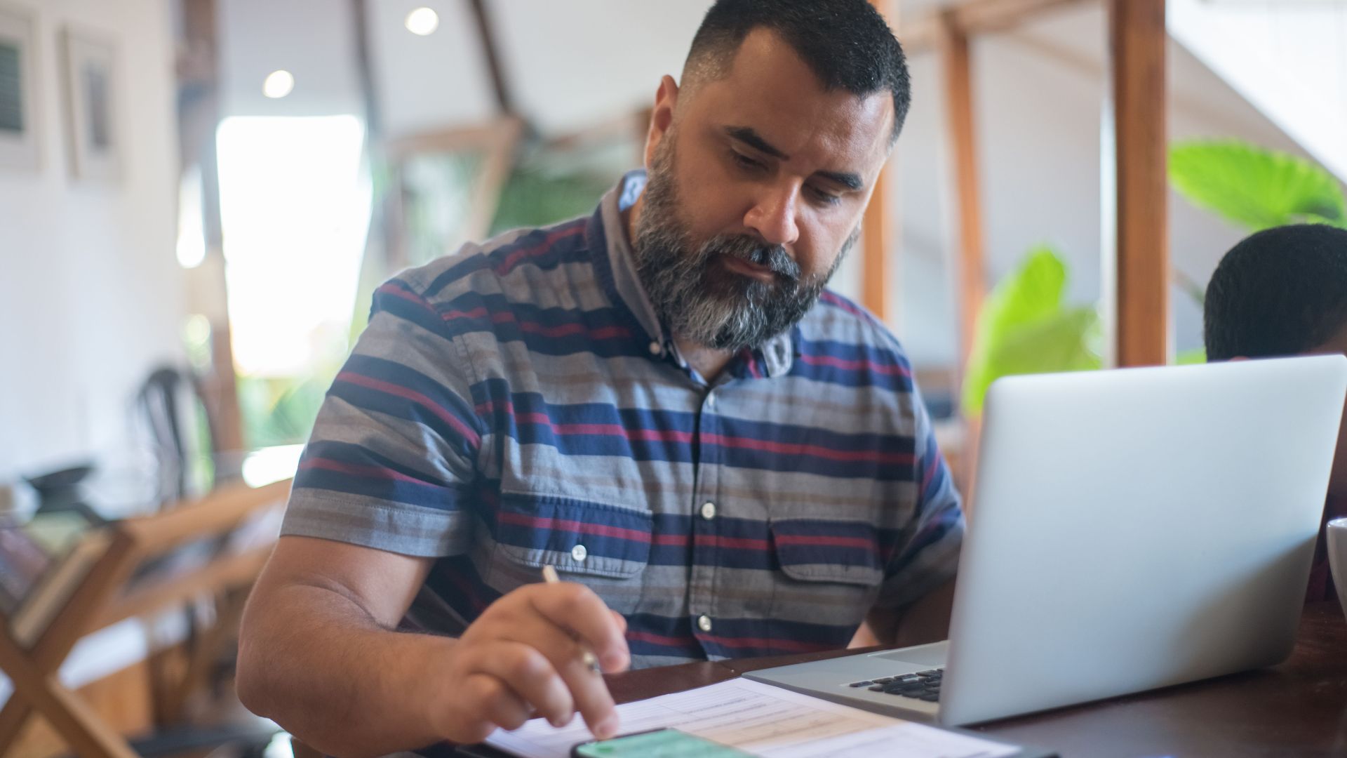 Professional man working at home office in Portugal using laptop and phone.