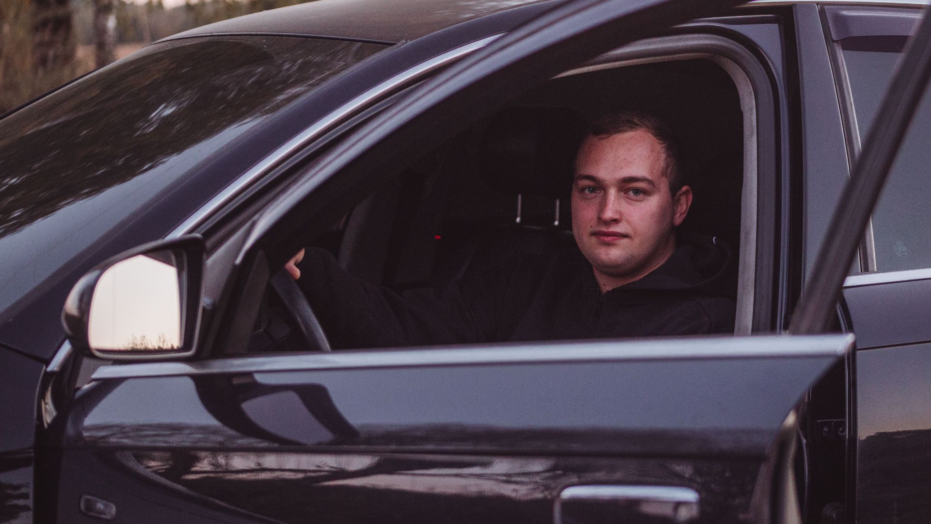 Male driver in a parked car during twilight, capturing a serene moment.