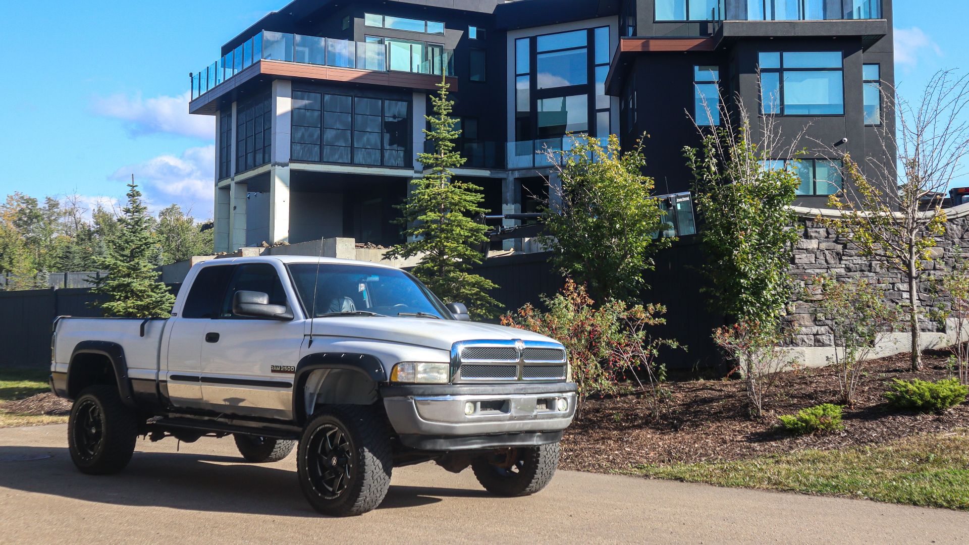 Stylish modern home with a parked silver pickup truck outdoors under a clear blue sky.