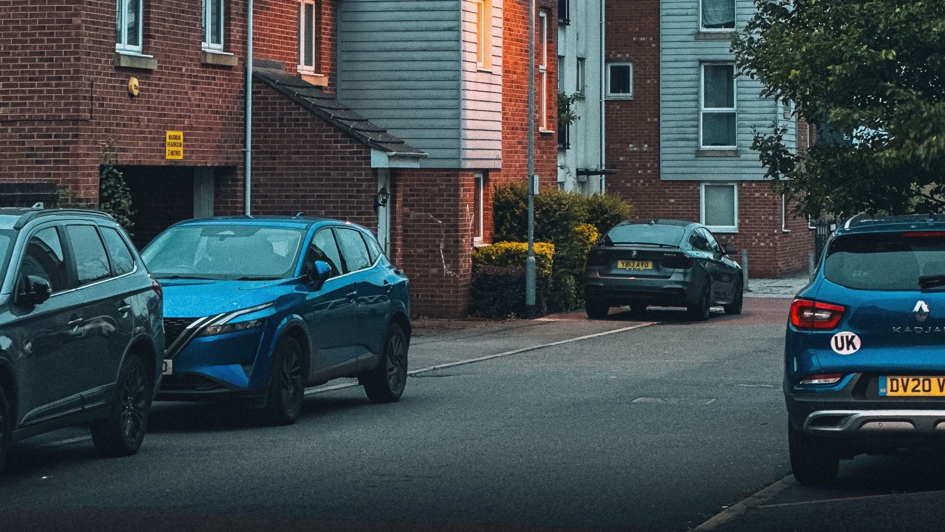 Evening view of a suburban residential area with parked cars lining the street.