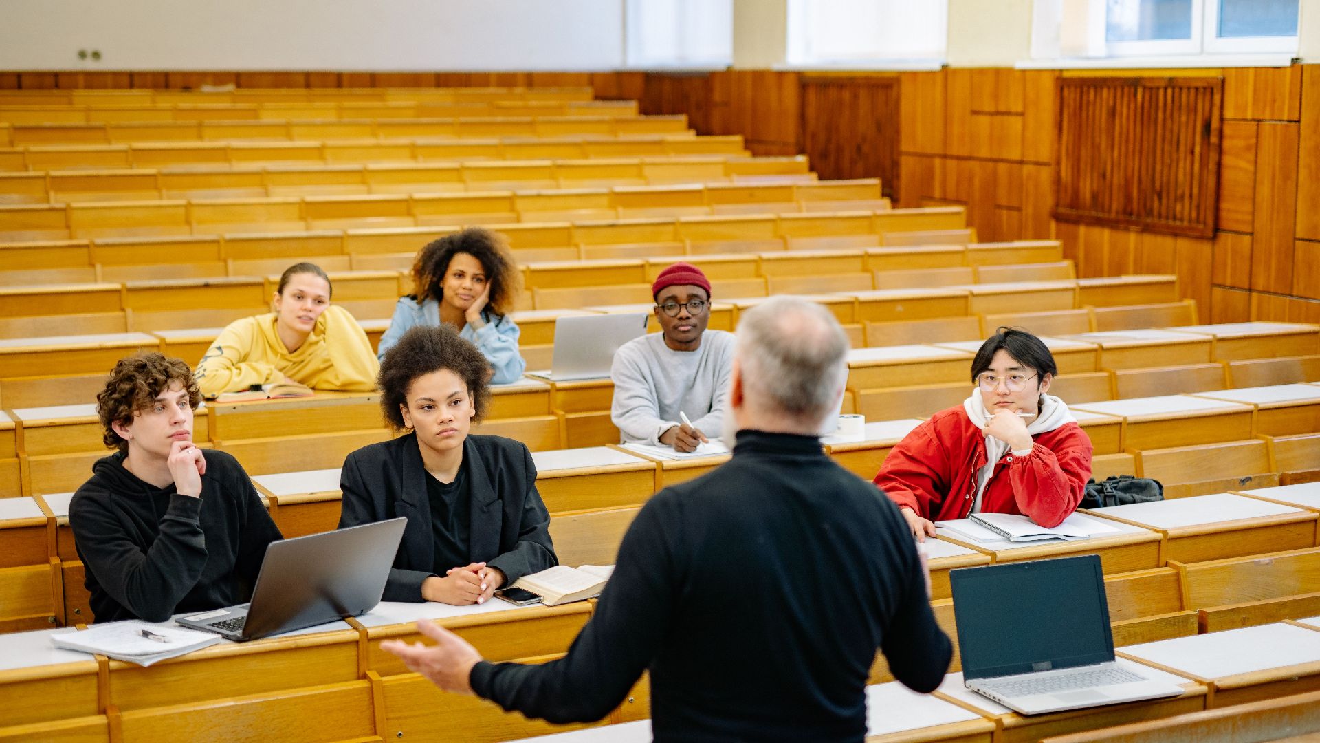 Professor teaching a diverse group of students in a university lecture hall.