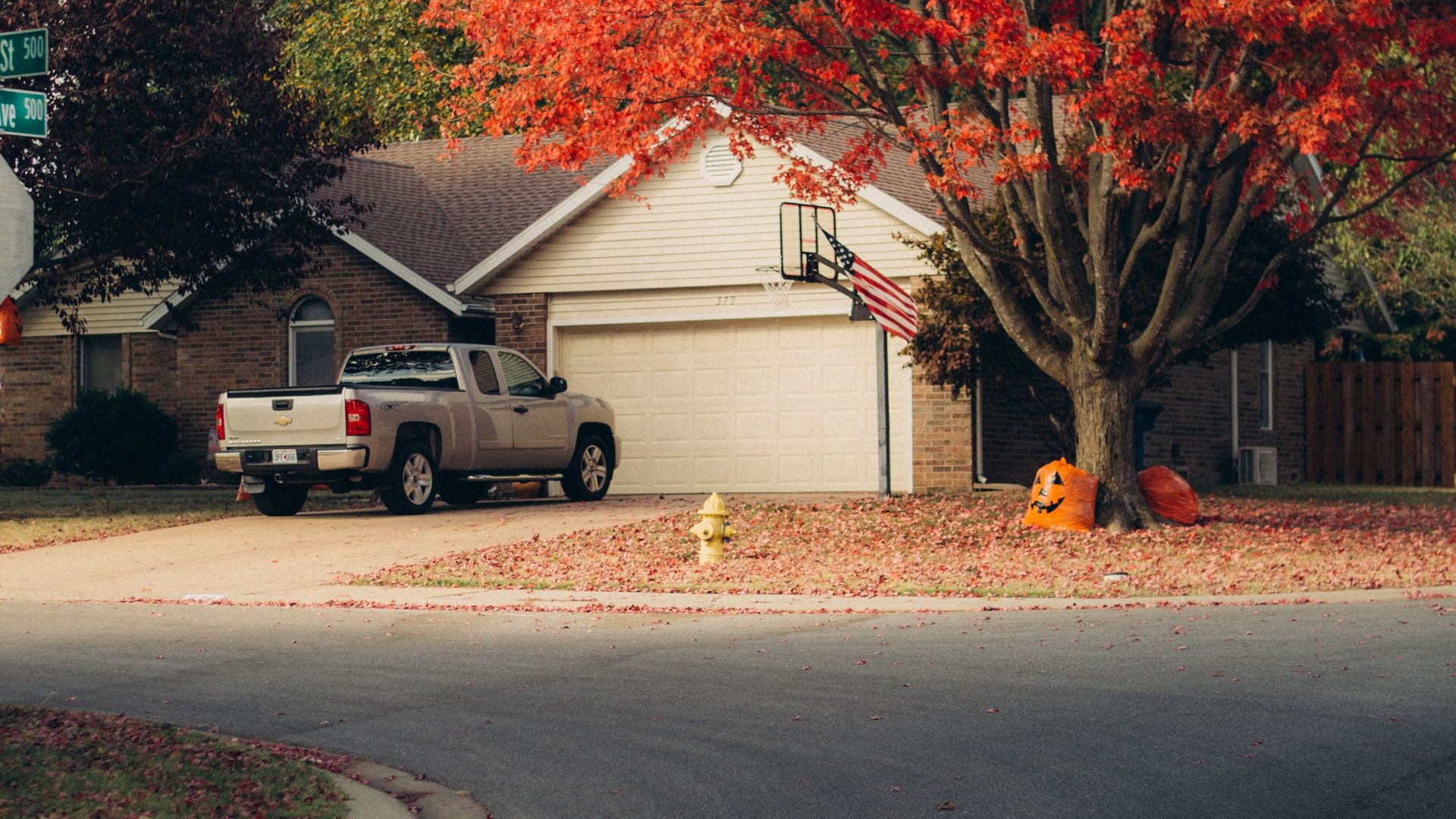 A quiet suburban street featuring vibrant autumn foliage and parked vehicle.