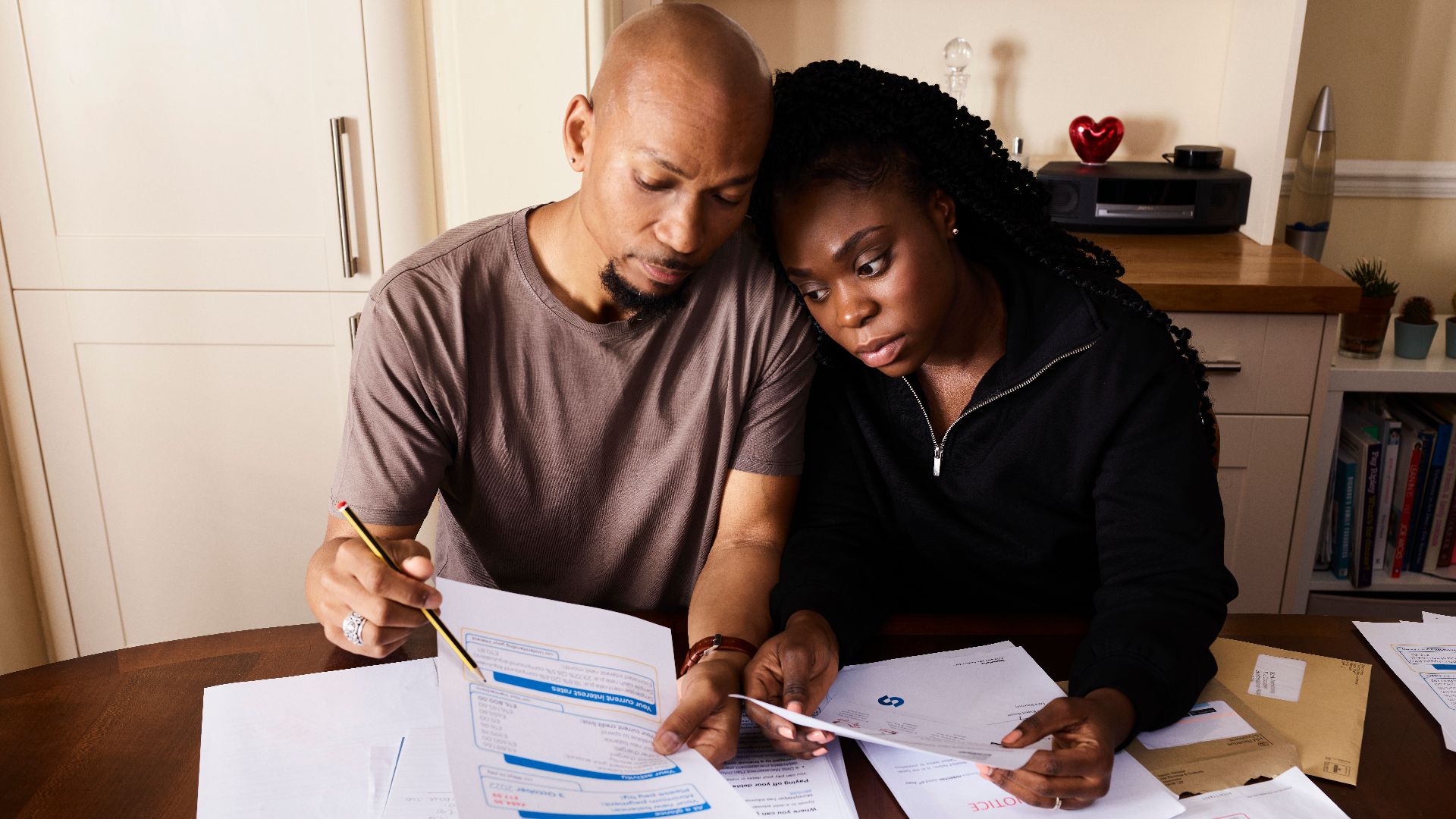 A couple sitting at a table reviewing financial documents, highlighting domestic budgeting.