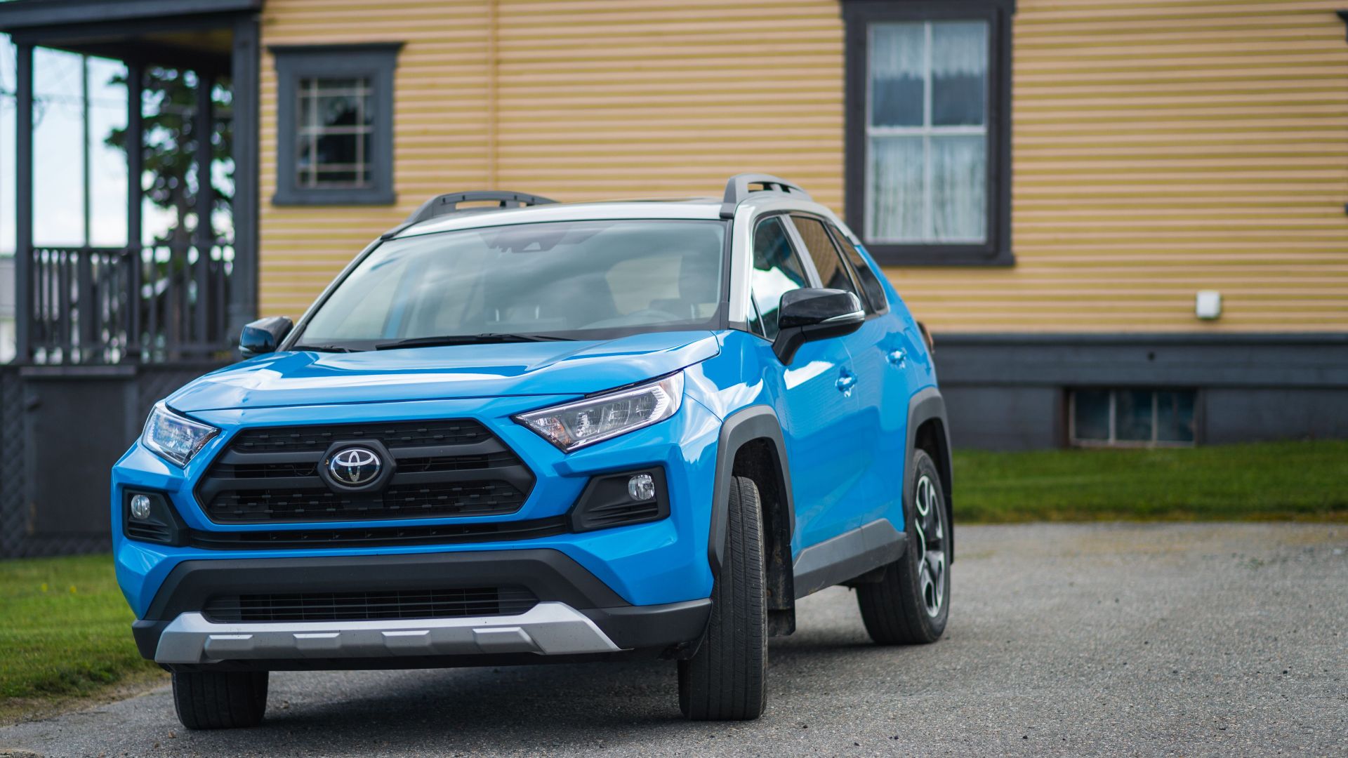 Blue Toyota RAV4 parked outside a house, showcasing modern SUV design.