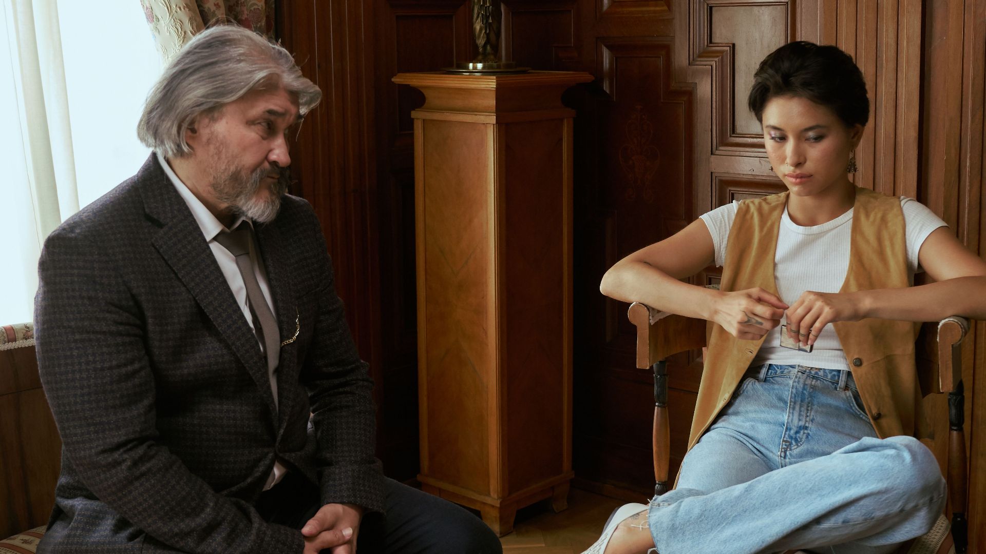 A father and daughter engaging in conversation in a luxurious living room setting.