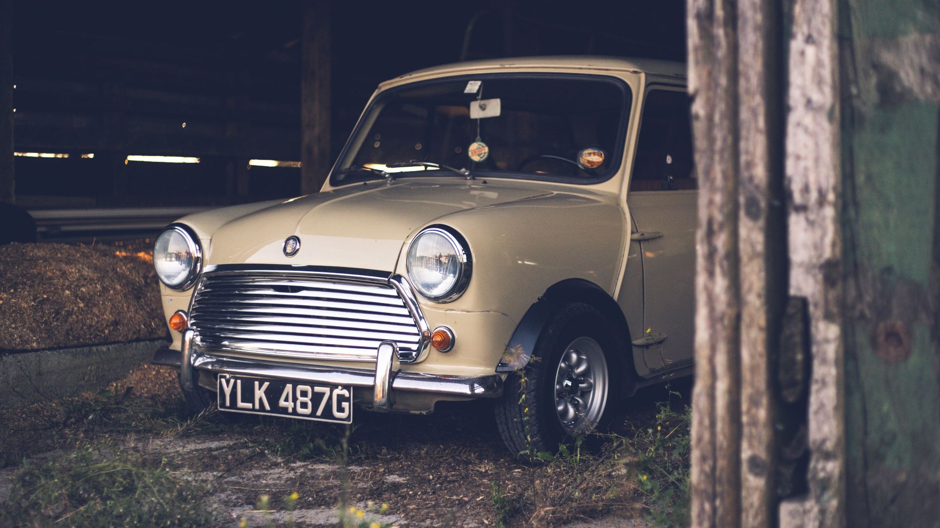 Stylish retro car placed on ground in old wooden barn in courtyard in daytime