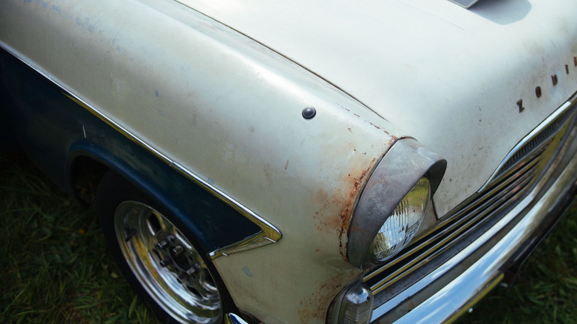 Close-up of a vintage car hood showing rust and classic features, perfect for antique enthusiasts.