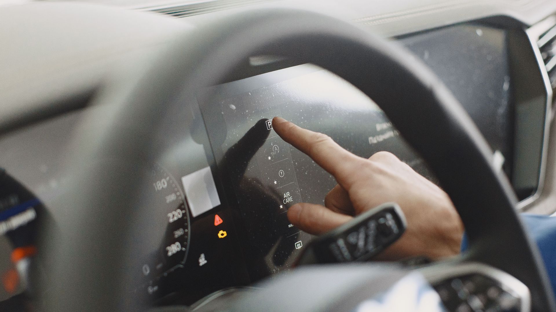 Close-up of a hand interacting with a car's digital dashboard. Modern technology and driving interface.