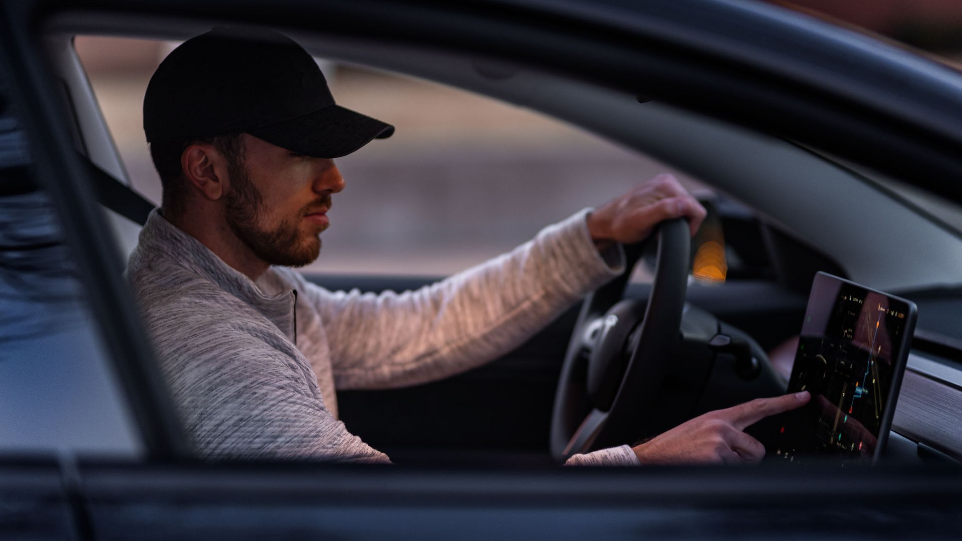 A man interacts with a touchscreen inside an electric car, driving through Dallas, TX.