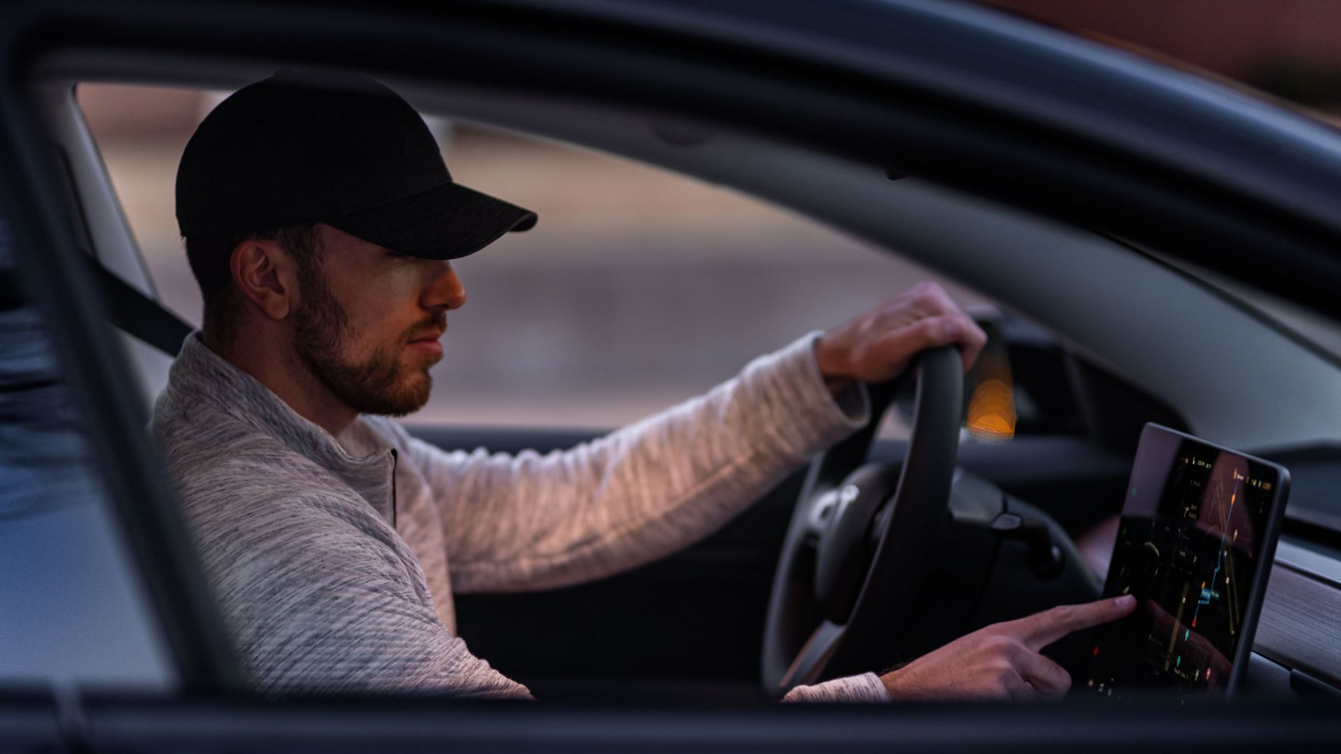 A man interacts with a touchscreen inside an electric car, driving through Dallas, TX.