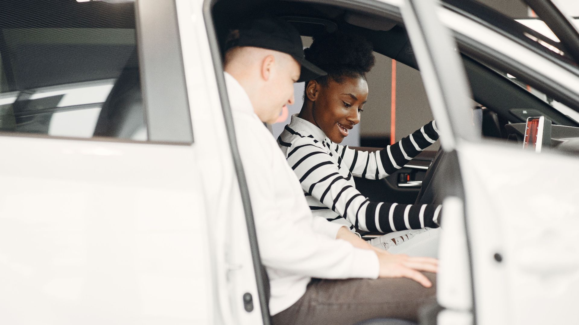 Two adults exploring a car interior at a dealership, smiling and engaged.