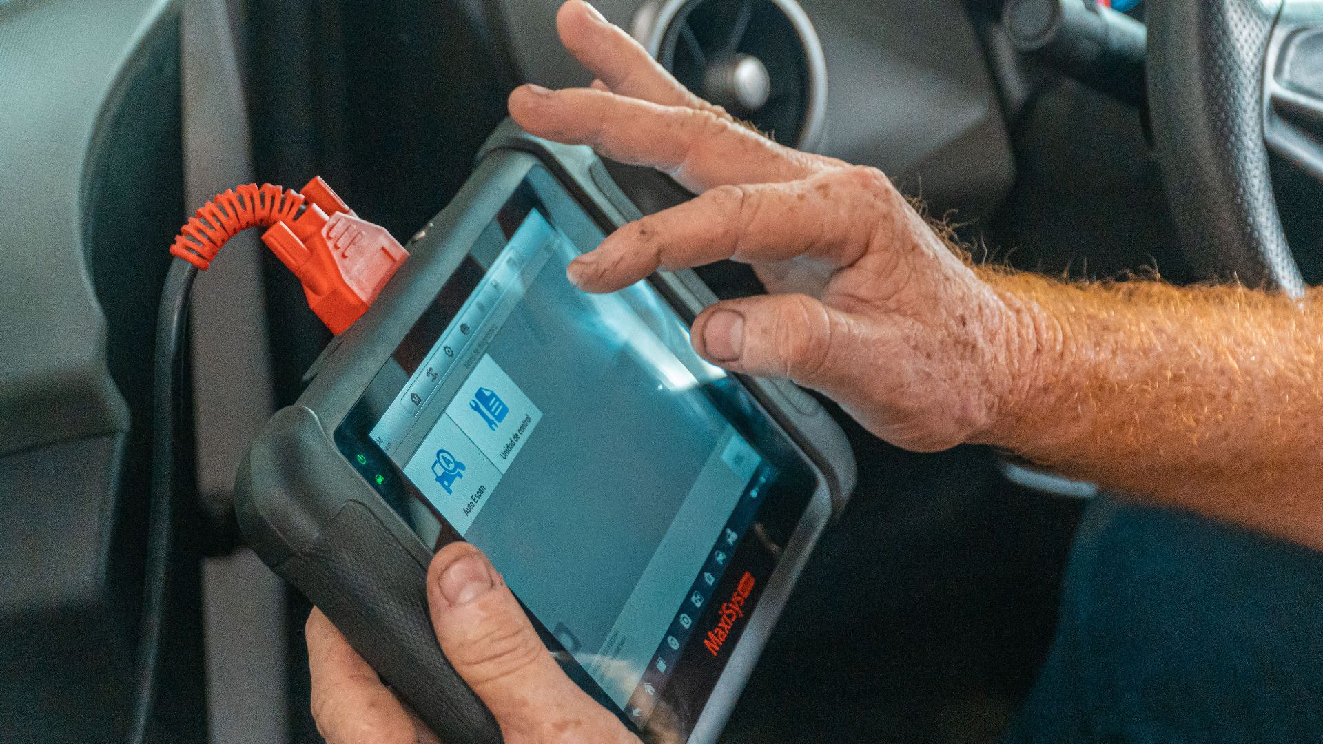 Mechanic using a diagnostic tool inside a car to check for engine issues and ensure proper maintenance.