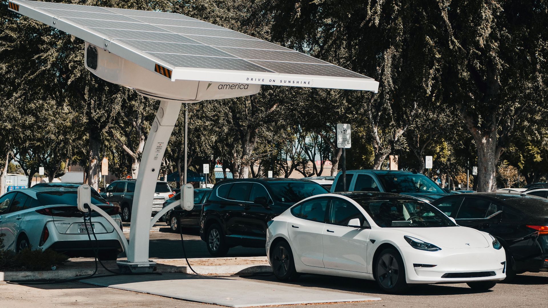 Electric car parked at a solar charging station outdoors, highlighting renewable energy and innovation.