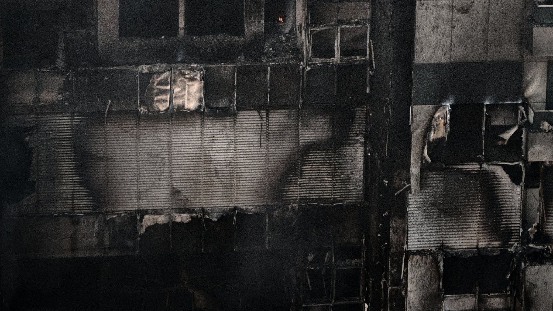 A towering building engulfed in flames and smoke, showing severe urban fire damage.