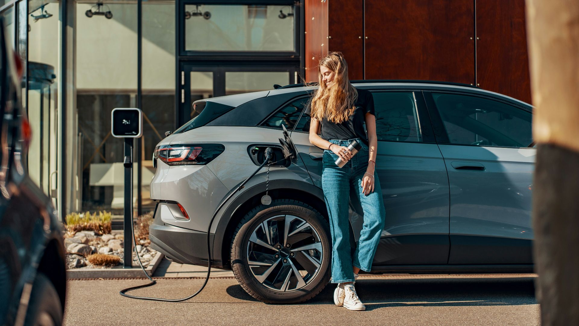 a woman standing next to a blue car