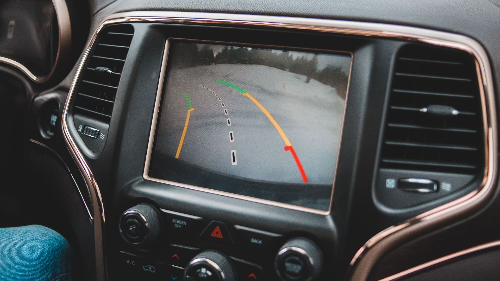 Close-up of a car's dashboard showing a rearview camera display for parking assistance.