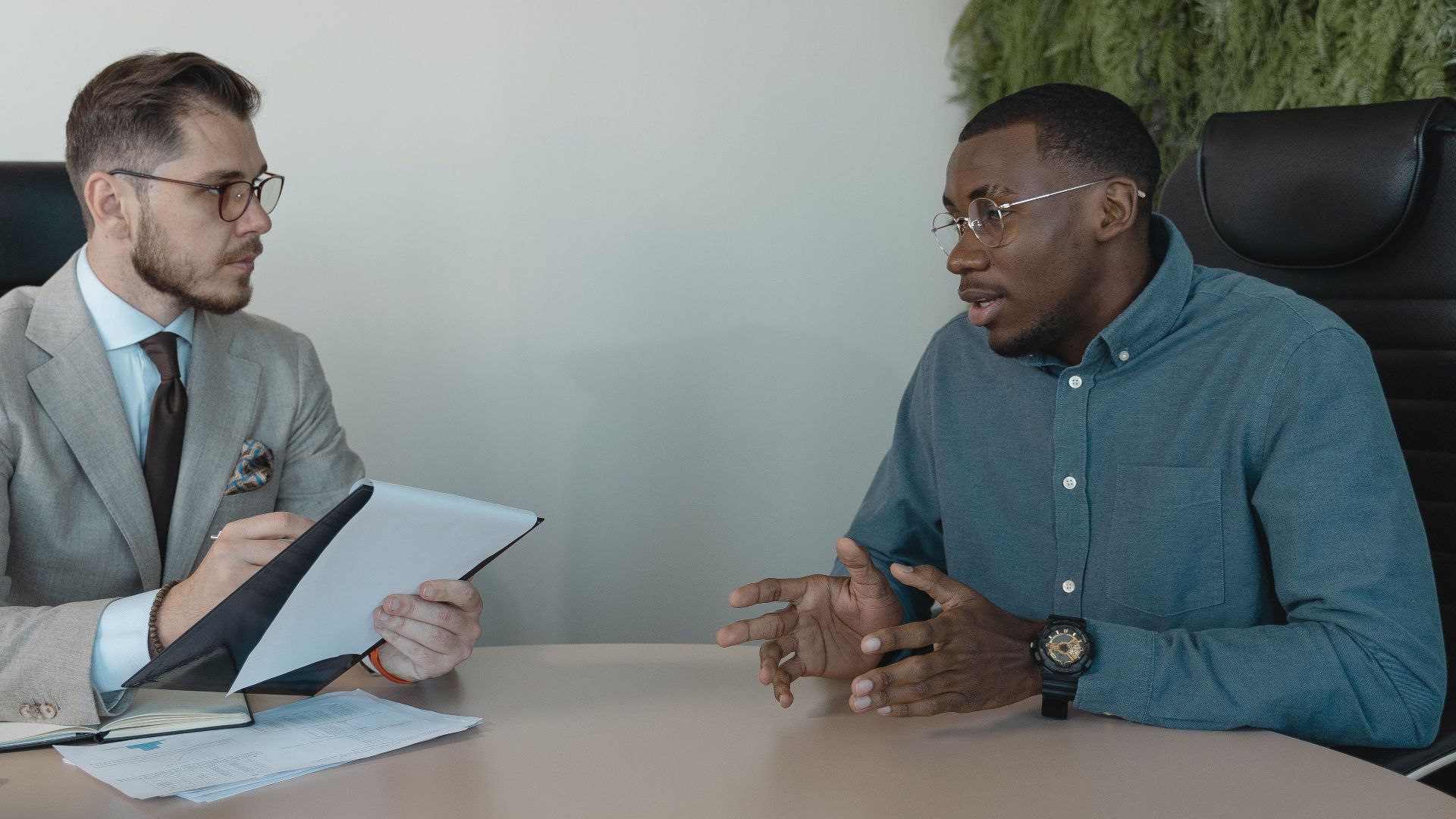 Two businessmen engaged in a discussion during a job interview in a contemporary office environment.