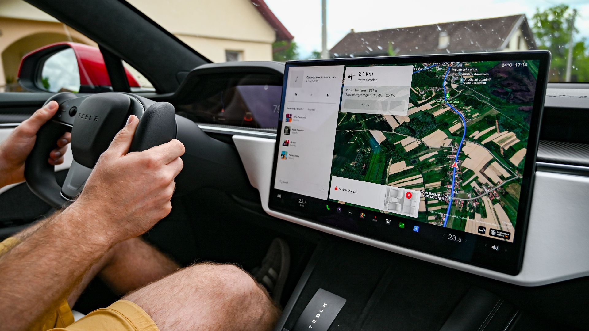 Man driving Tesla using GPS on touchscreen dashboard for navigation.