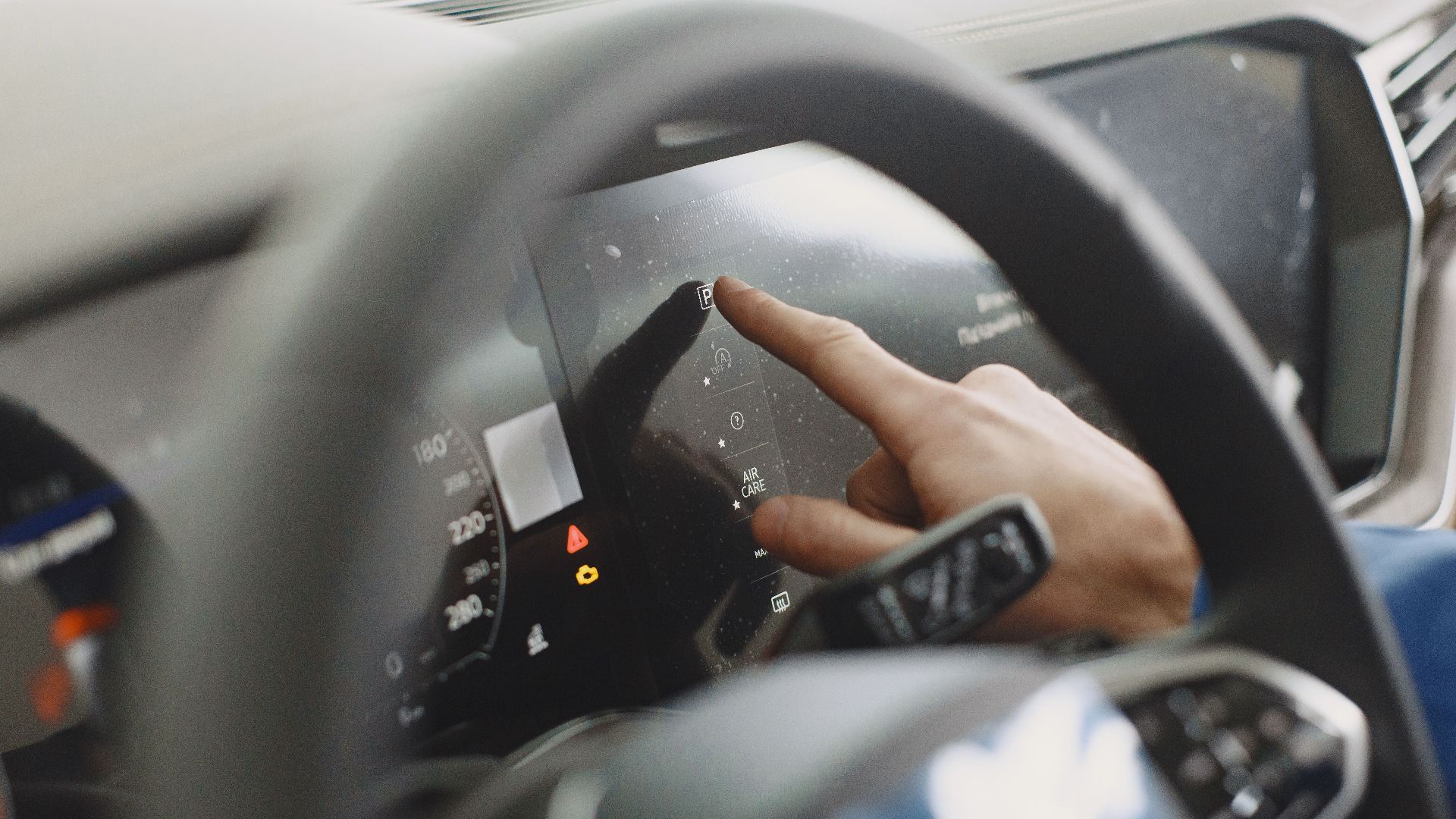 Close-up of a hand interacting with a car's digital dashboard. Modern technology and driving interface.