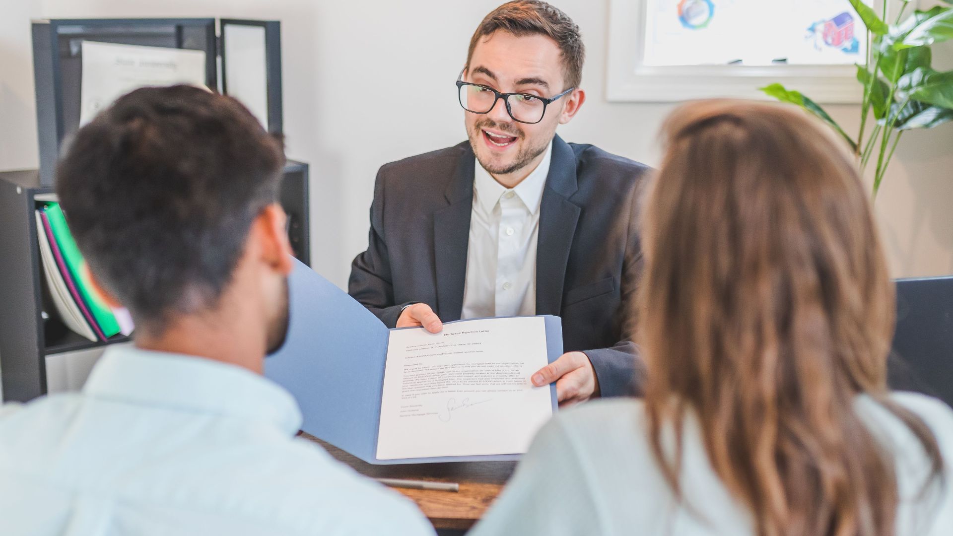 A businessman discusses a contract with clients in a modern office setting.