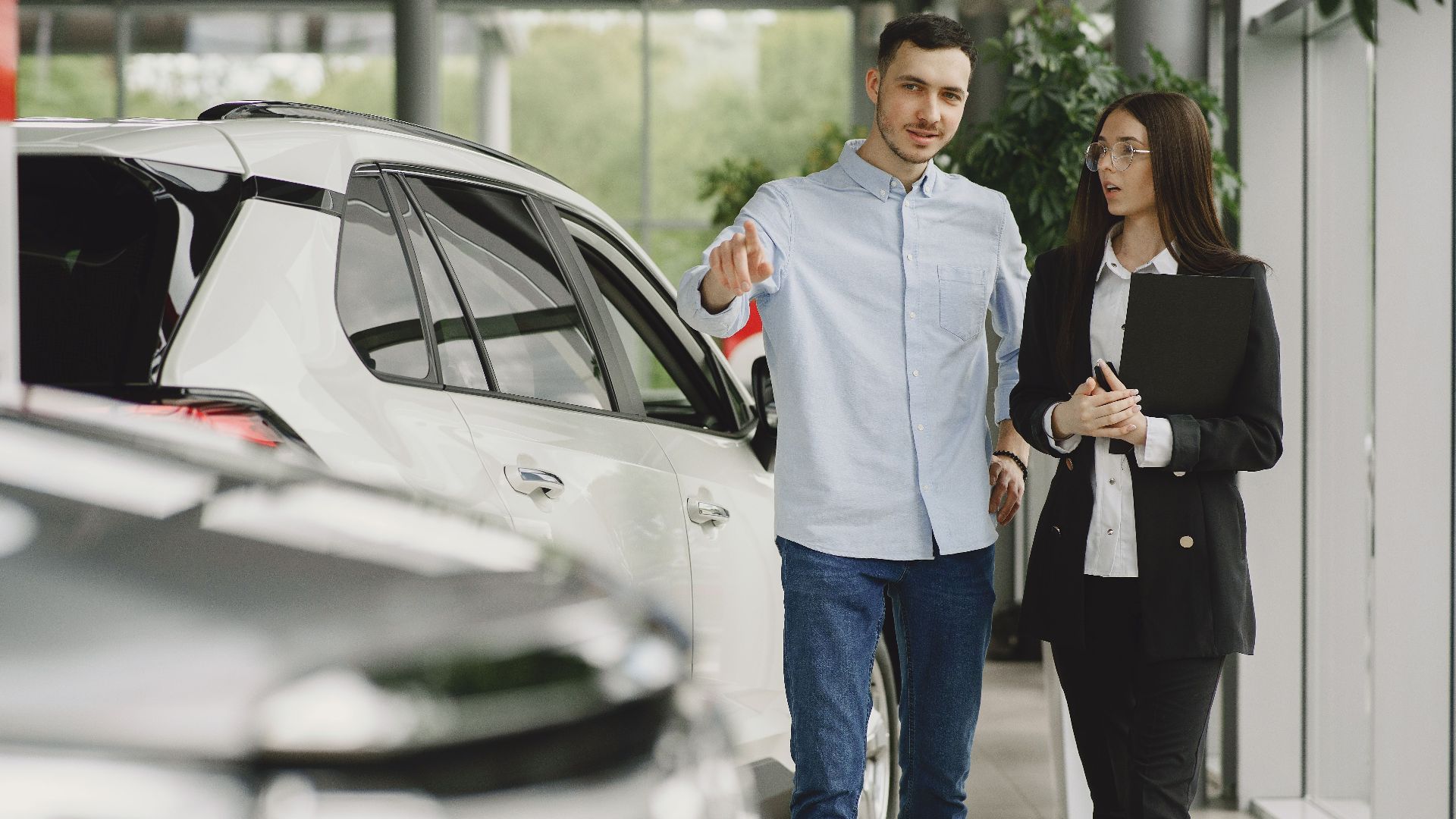 Customer and salesperson discussing a vehicle inside a modern car dealership showroom.