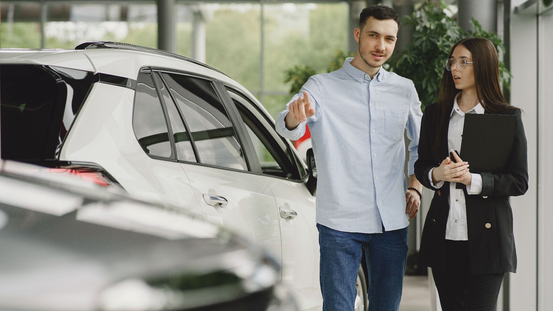 Customer and salesperson discussing a vehicle inside a modern car dealership showroom.