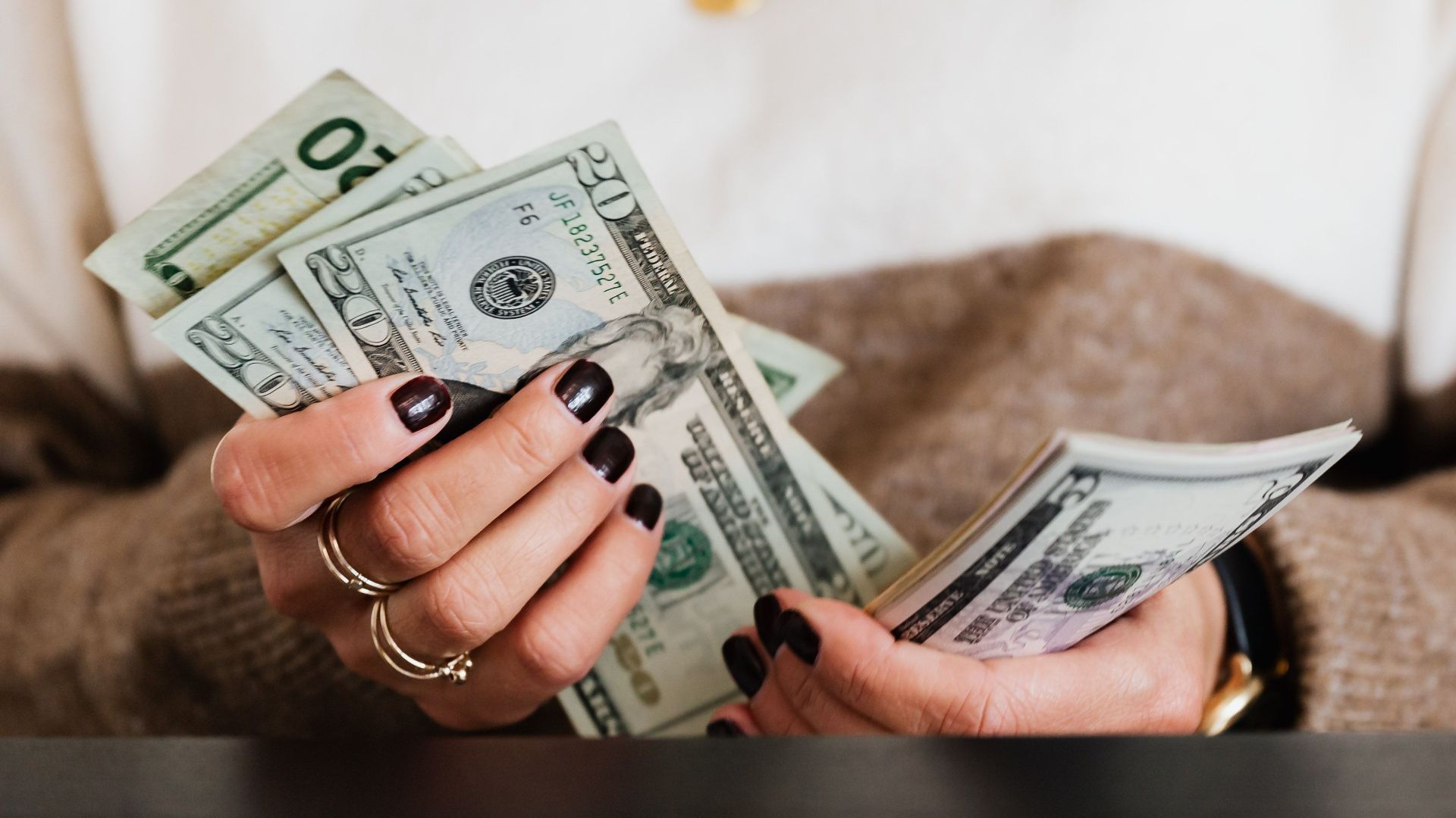 Close-up of hands counting US dollar bills, depicting finance and money handling.