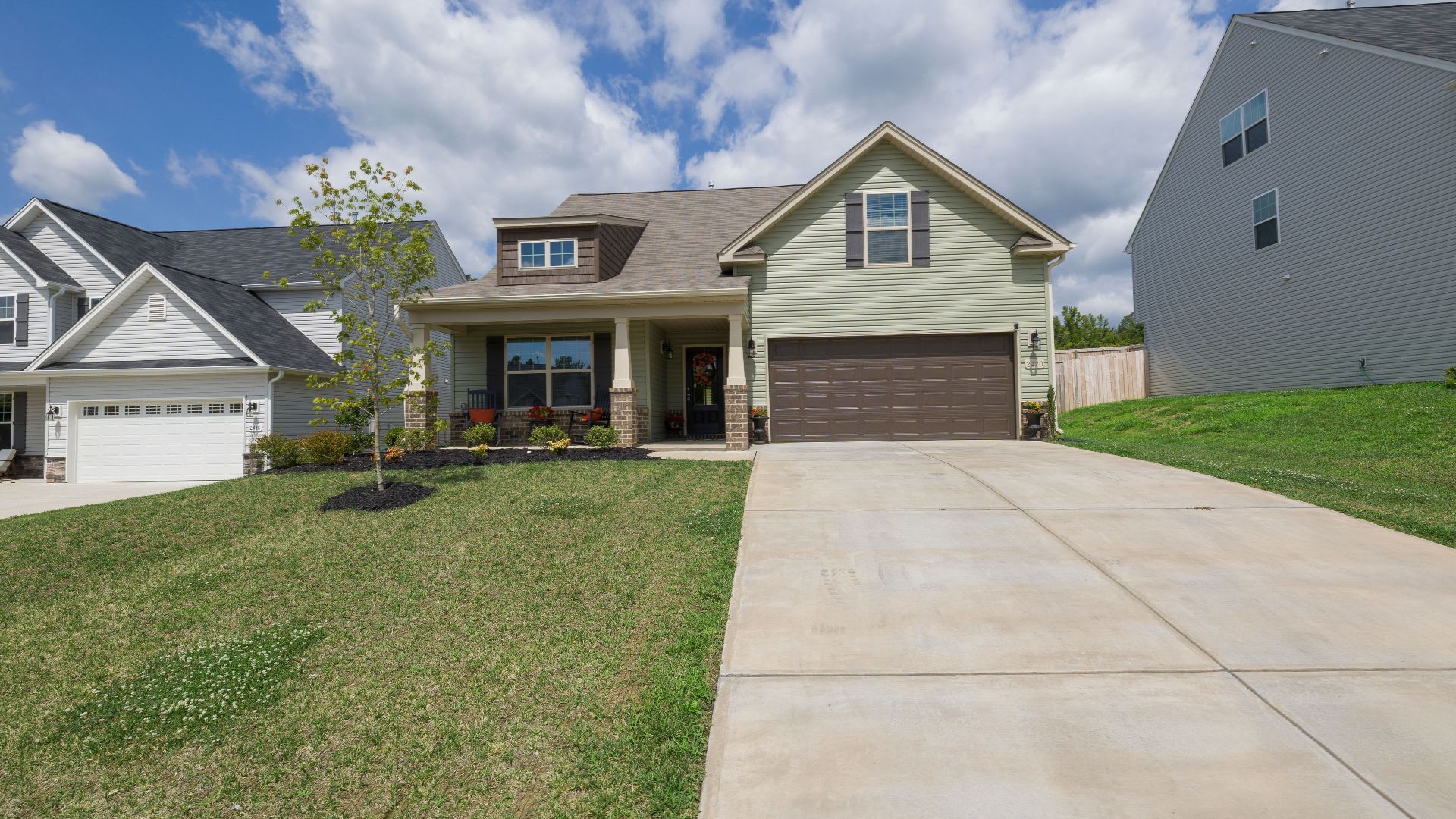 A modern suburban detached house with a spacious driveway under a bright blue sky.